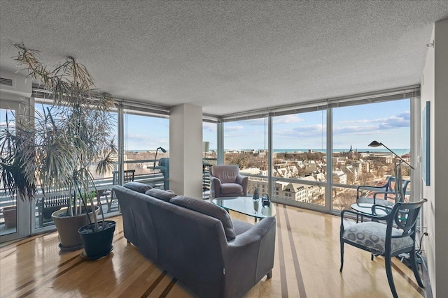 living room with a wall of windows, wood finished floors, and a textured ceiling