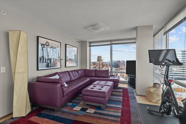 living area with visible vents, a healthy amount of sunlight, a textured ceiling, and a wall of windows