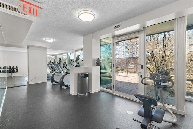 gym with visible vents, a healthy amount of sunlight, and a textured ceiling