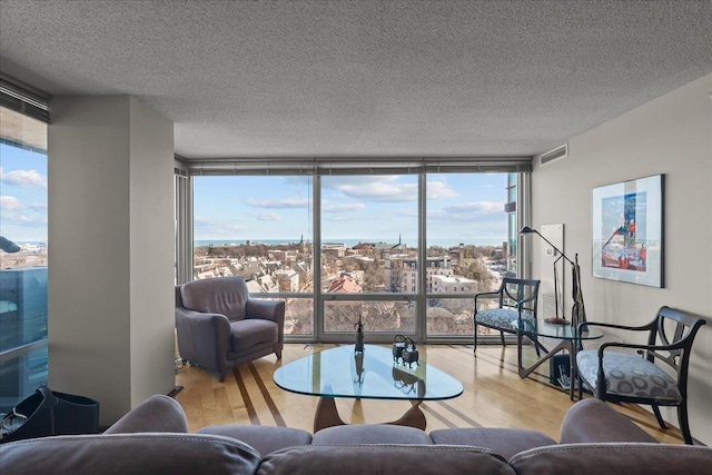 living room featuring expansive windows, a textured ceiling, visible vents, and wood finished floors