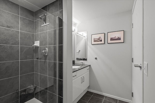 bathroom featuring tile patterned flooring, baseboards, vanity, and a tile shower