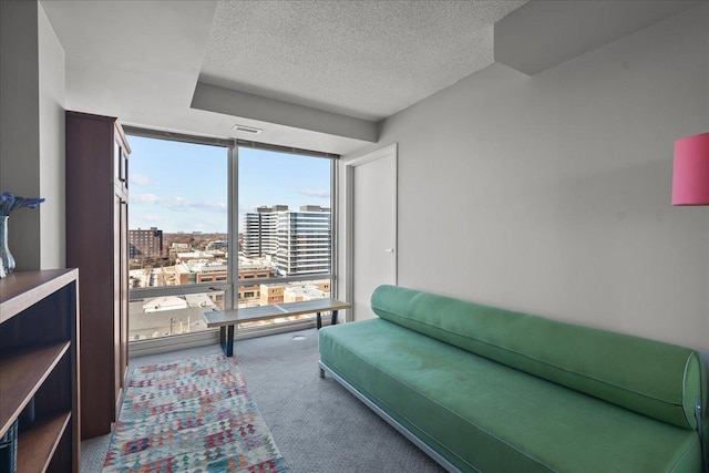 living room with visible vents, expansive windows, carpet flooring, a view of city, and a textured ceiling