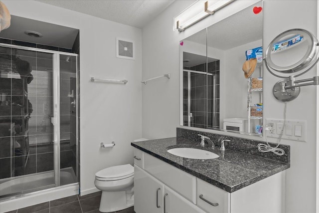 bathroom featuring vanity, a stall shower, a textured ceiling, tile patterned floors, and toilet