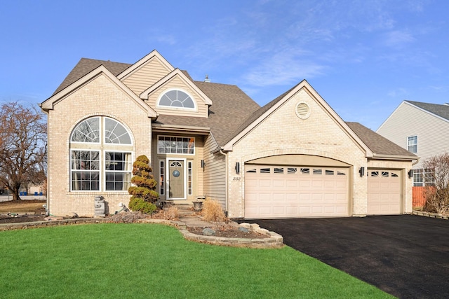 traditional home with a front lawn, driveway, roof with shingles, a garage, and brick siding