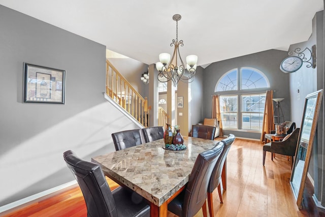 dining room featuring light wood-type flooring, stairway, baseboards, and an inviting chandelier