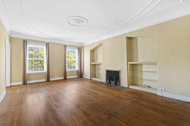 unfurnished living room with hardwood / wood-style floors, built in features, baseboards, a fireplace, and ornamental molding