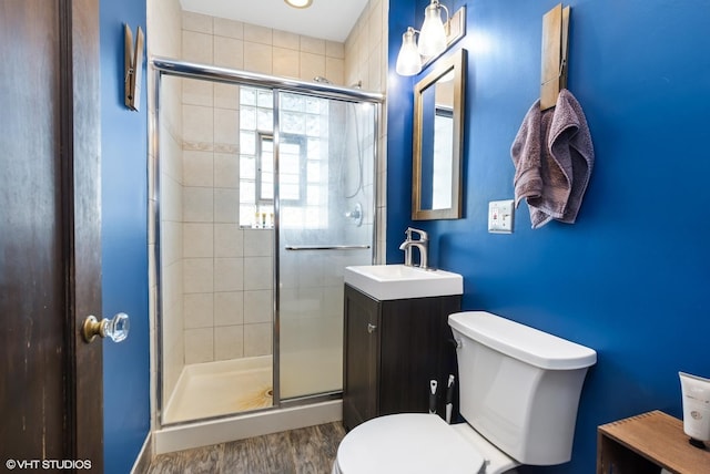 bathroom featuring a shower stall, toilet, vanity, and wood finished floors