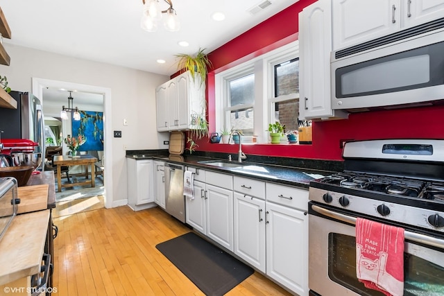 kitchen with visible vents, a sink, white cabinetry, stainless steel appliances, and an inviting chandelier