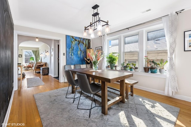 dining room featuring visible vents, baseboards, an inviting chandelier, arched walkways, and wood-type flooring