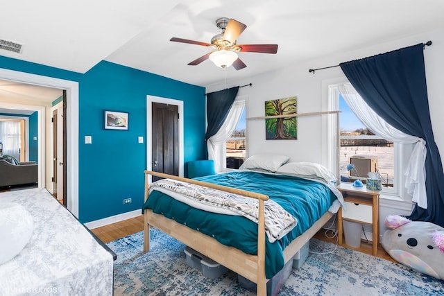 bedroom featuring ceiling fan, visible vents, baseboards, and wood finished floors