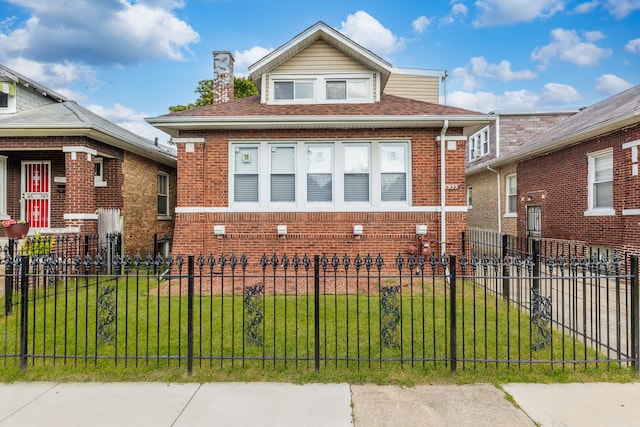 bungalow featuring a fenced front yard, brick siding, and a front lawn