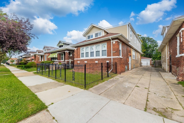 view of front of property featuring brick siding, a residential view, a fenced front yard, and a front yard