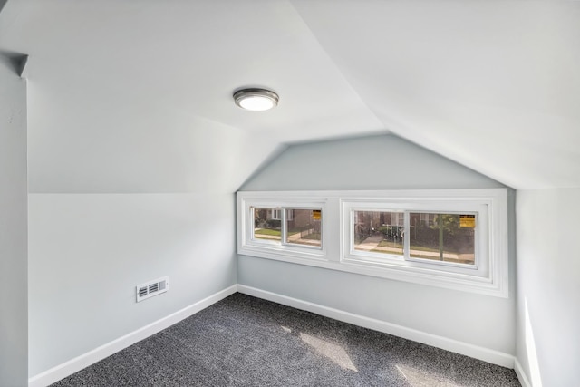 bonus room with visible vents, dark colored carpet, baseboards, and vaulted ceiling