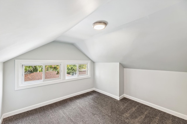 bonus room featuring baseboards, dark carpet, and vaulted ceiling