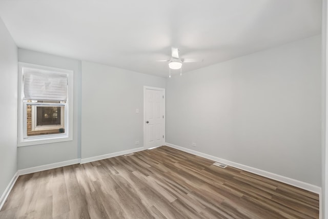 spare room with wood finished floors, baseboards, visible vents, and ceiling fan