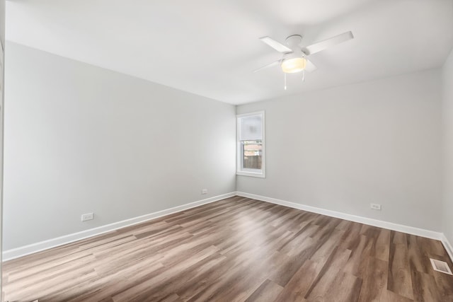 spare room with visible vents, ceiling fan, baseboards, and wood finished floors