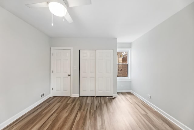 unfurnished bedroom featuring a closet, ceiling fan, baseboards, and wood finished floors