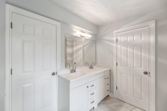 bathroom with double vanity, marble finish floor, and a sink