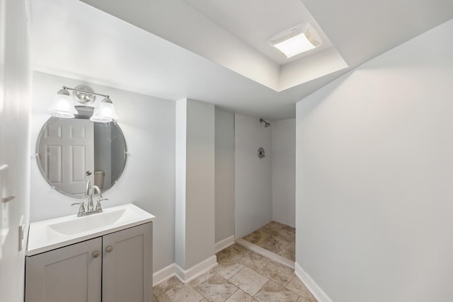 bathroom with vanity, baseboards, and a tile shower