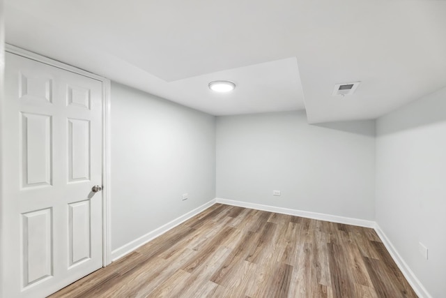 finished basement with visible vents, light wood-style floors, and baseboards