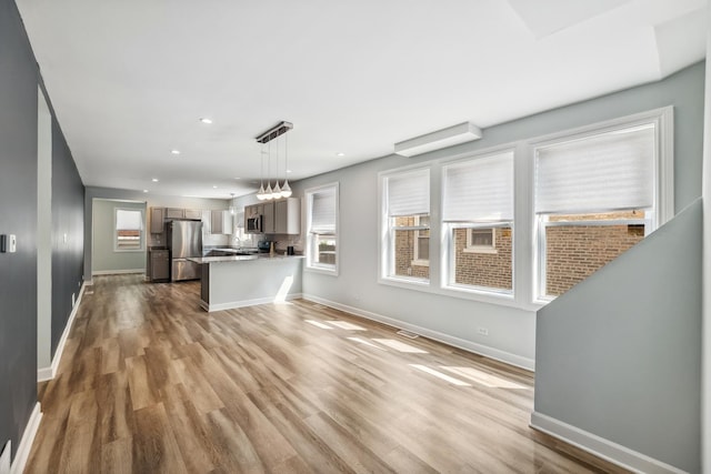 kitchen with baseboards, plenty of natural light, appliances with stainless steel finishes, and wood finished floors