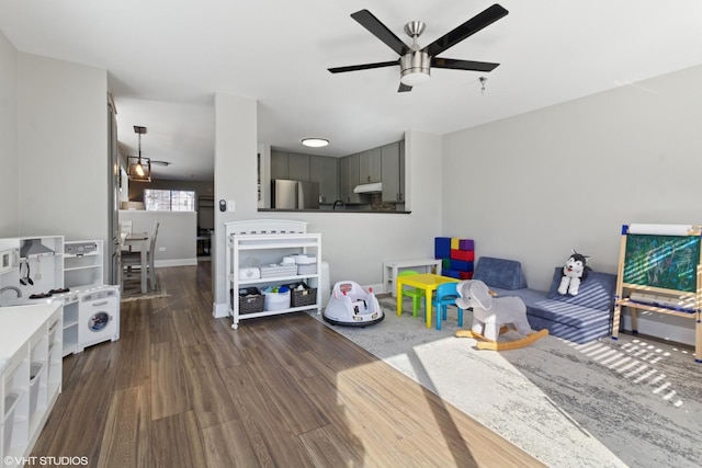 game room featuring a ceiling fan, dark wood-style floors, and baseboards