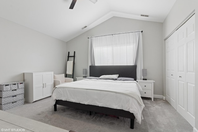 bedroom featuring a closet, visible vents, light colored carpet, and lofted ceiling