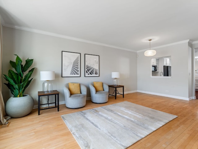 living area featuring light wood-style flooring, crown molding, and baseboards