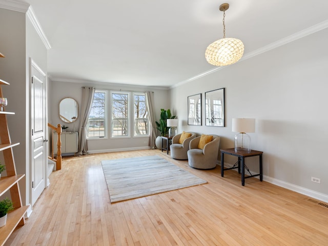 living area with visible vents, light wood-type flooring, baseboards, and ornamental molding