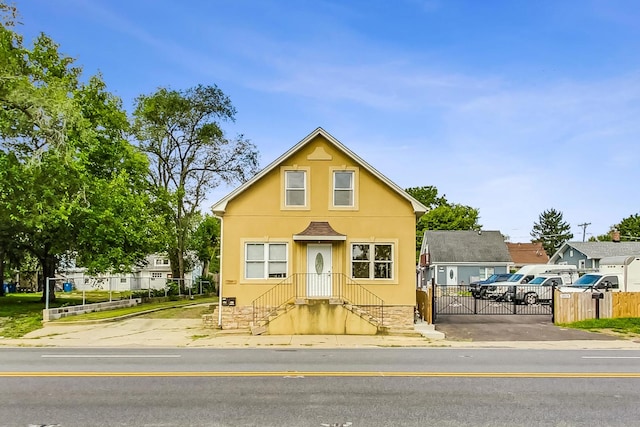 bungalow-style house with a gate, a residential view, stucco siding, and fence