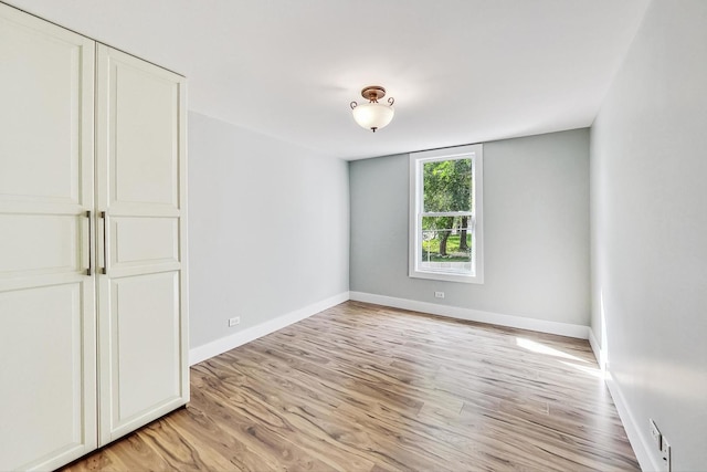 unfurnished bedroom with baseboards, light wood-type flooring, and a closet