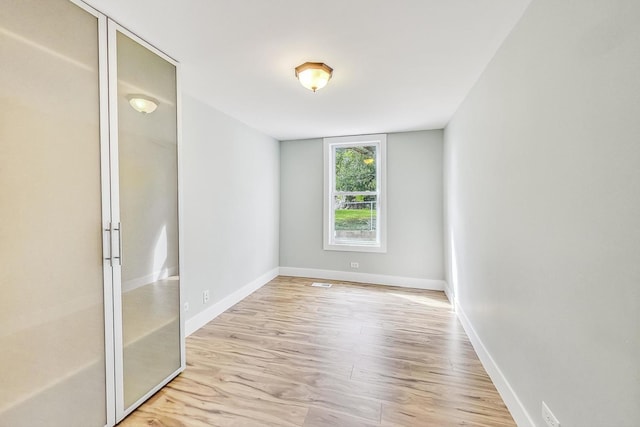 spare room with baseboards and wood finished floors