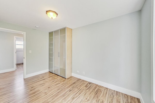 unfurnished bedroom featuring baseboards, light wood-type flooring, and a closet