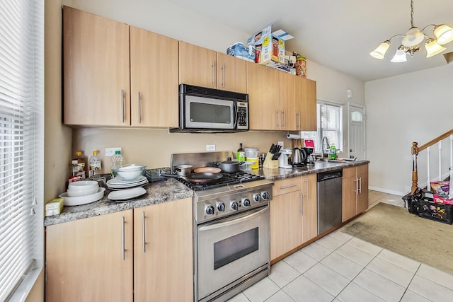 kitchen with a notable chandelier, pendant lighting, a sink, appliances with stainless steel finishes, and light tile patterned floors