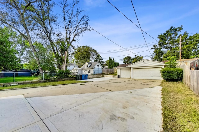 view of front facade with an outbuilding, a detached garage, and fence