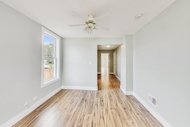 spare room featuring a ceiling fan, light wood-style flooring, baseboards, and visible vents