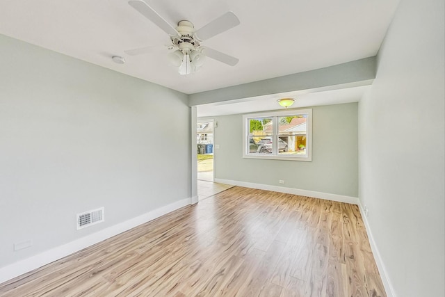 spare room with a ceiling fan, wood finished floors, visible vents, and baseboards