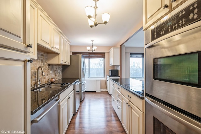 kitchen with cream cabinets, a notable chandelier, stainless steel appliances, and a sink