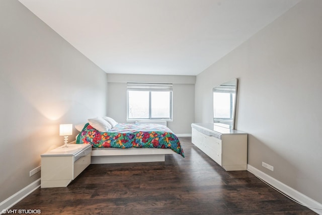 bedroom with dark wood-type flooring and baseboards