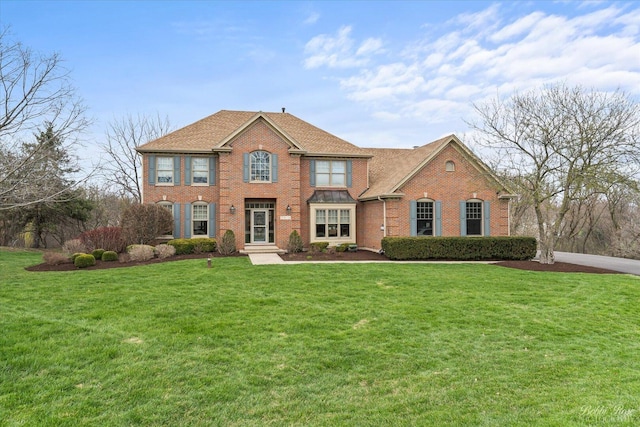 view of front of house with roof with shingles, brick siding, and a front yard