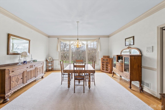 dining room featuring ornamental molding, light wood-type flooring, an inviting chandelier, and visible vents