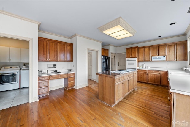 kitchen featuring ornamental molding, a sink, white appliances, and washer and clothes dryer