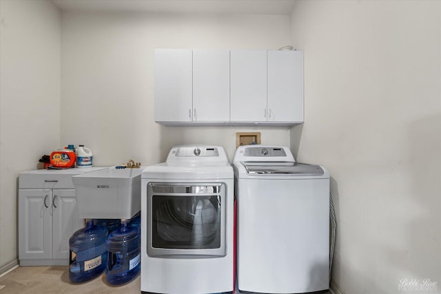 laundry area featuring separate washer and dryer, a sink, and cabinet space