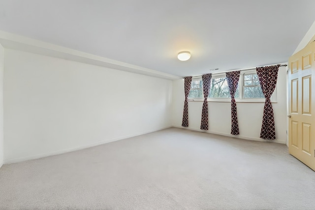 unfurnished room featuring light carpet and baseboards