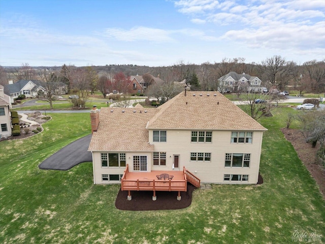 rear view of house with a yard, a wooden deck, and a chimney