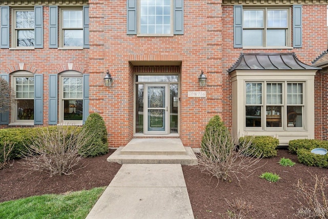 entrance to property featuring brick siding, metal roof, and a standing seam roof