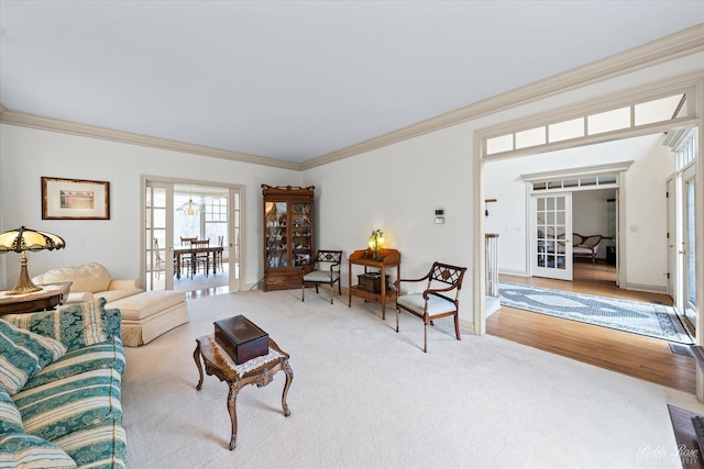living area featuring baseboards, crown molding, carpet floors, wood finished floors, and french doors