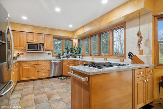 kitchen with tasteful backsplash, appliances with stainless steel finishes, and light countertops