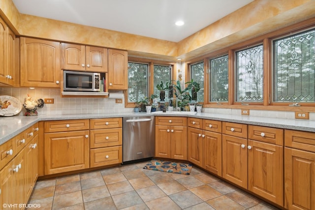 kitchen featuring decorative backsplash, light stone countertops, brown cabinets, and appliances with stainless steel finishes