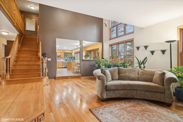 living area featuring stairway, a high ceiling, and light wood finished floors